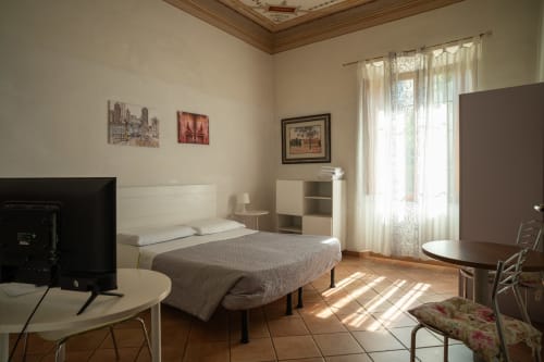 Camera doppia luminosa a Casa di Alfredo B&B a Siena con vista sul giardino, letto, TV, scrivania e bagno in comune