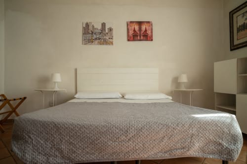 Camera luminosa e minimalista a Casa di Alfredo B&B a Siena con letto queen size, testata bianca, biancheria neutra, lampade comodino