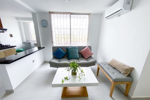 Sala de estar moderna en Olamar Living con sofá gris, mesa de centro blanca y área de cocina en Santiago de Tolú