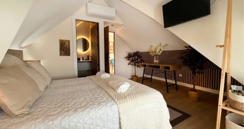Habitación moderna en ático de La Posada de las Flores con cama doble, baño privado, escritorio y televisor de pantalla plana