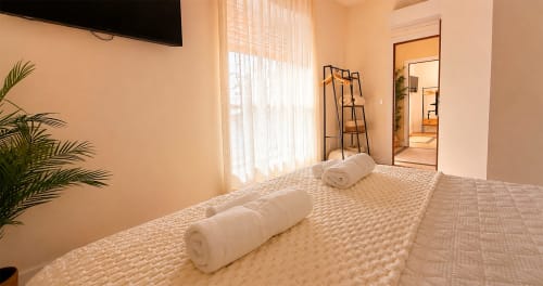 Amplia habitación doble en hotel La Posada de las Flores con toallas enrolladas en la cama, plantas y luz natural de la ventana