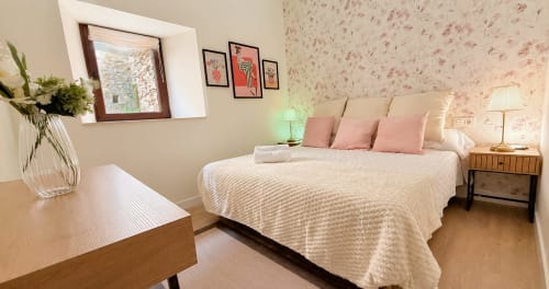 Elegante habitación doble en el hotel La Posada de las Flores de España con ropa de cama crema, papel tapiz floral rosa y madera