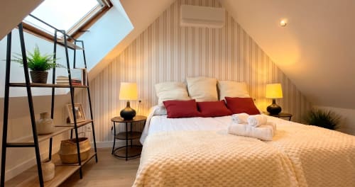 Acogedora habitación doble en La Posada de las Flores con techo inclinado, claraboya, almohadas rojas, iluminación cálida y diseño moderno
