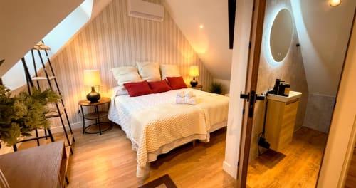 Dormitorio tipo loft moderno en La Posada de las Flores con cama queen, almohadas rojas y baño privado en España