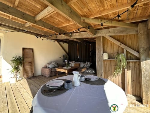 La terrasse en bois de La Belle Époque avec table à manger, salon et poutres apparentes à Kerlaz