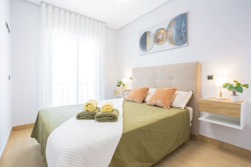 Modern bedroom at Haus Holiday Homes in Los Alcázares with queen bed, striped pillows, and sea-view balcony