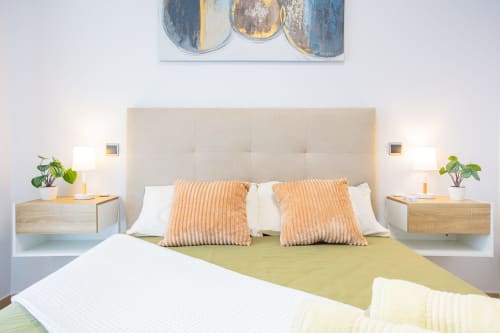 Modern bedroom at Haus Holiday Homes in Los Alcázares with beige headboard, orange pillows, wooden nightstands, and sea view