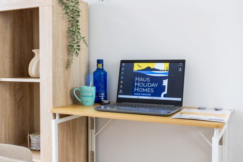 Modern apartment workspace at Haus Holiday Homes with laptop displaying Mar Menor views, wooden desk with decor
