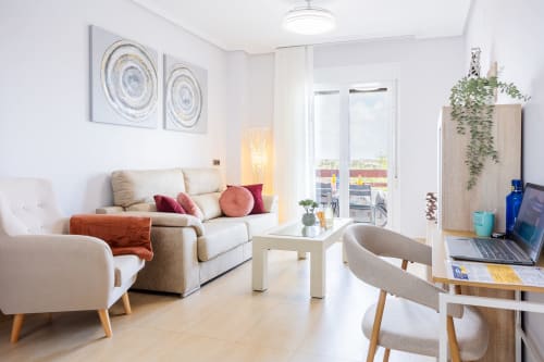 Modern apartment living room at Haus Holiday Homes, Los Alcázares with sea view, beige sofa, armchair, and work desk