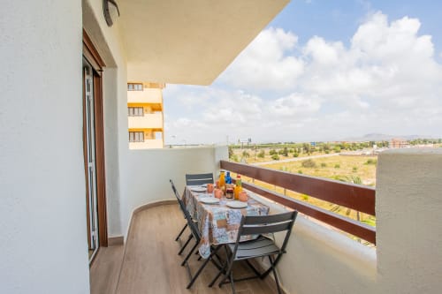 Balcony dining area at Haus Holiday Homes apartment in Los Alcázares with sea view and countryside landscape