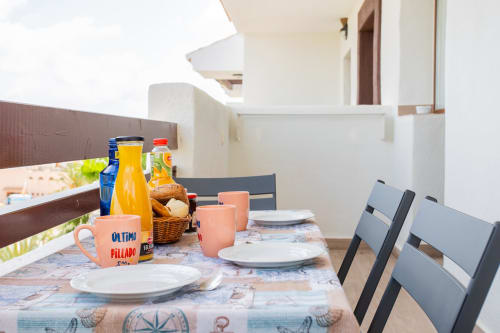 Terrace dining setup at Haus Holiday Homes with sea views, laid table, orange tableware, and breakfast items