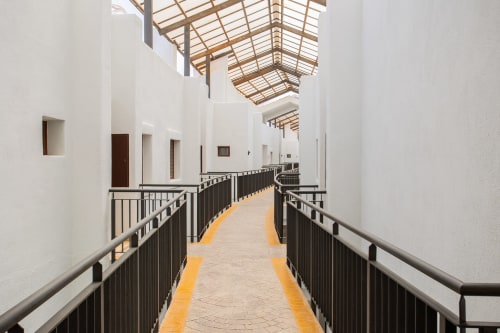 Modern covered corridor with white walls, yellow stripe flooring, and metal railings at Haus Holiday Homes, Los Alcázares
