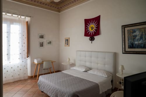 Camera luminosa a Casa di Alfredo, Siena con letto matrimoniale, testata crema, finestre con vista sul giardino e arazzi solari decorativi