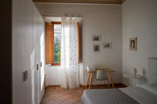 Camera luminosa di Casa di Alfredo B&B a Siena con scrivania in legno, finestra vista giardino e muri imbiancati