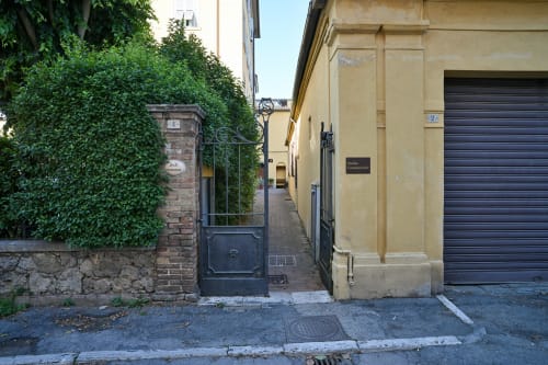 Stretto ingresso di una viuzza verso Casa di Alfredo B&B a Siena, con cancellata ricoperta di edera e edifici in cotto