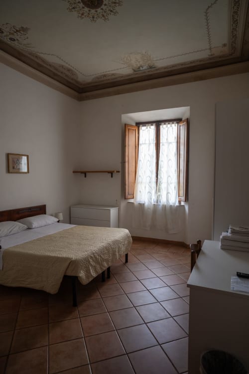 Camera luminosa di Casa di Alfredo B&B a Siena con pavimento in cotto, letto singolo e vista sulla campagna dalle finestre alte