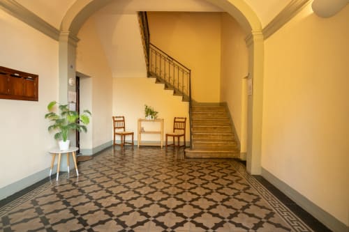 Elegante corridoio di Casa di Alfredo a Siena con pavimentazione in maiolica geometrica, scala in legno e classici archi architettonici