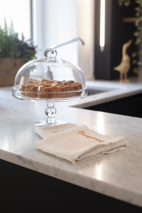 Glass cake dome with pastries on marble counter at Camere d'Aria, a boutique bed and breakfast in Locana, Italy