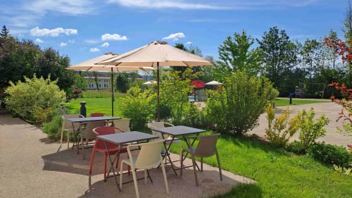 Terrasse ombragée avec parasols à La Pause ô Logis B&B à Saint Laurent en Grandvaux, entourée de verdure.