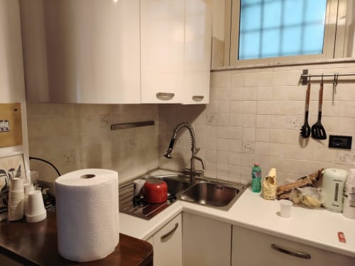 Cucina moderna nell'appartamento Quinqueremi a ViOletta, Lido di Ostia con lavello in acciaio inox, mobili bianchi e piastrellato