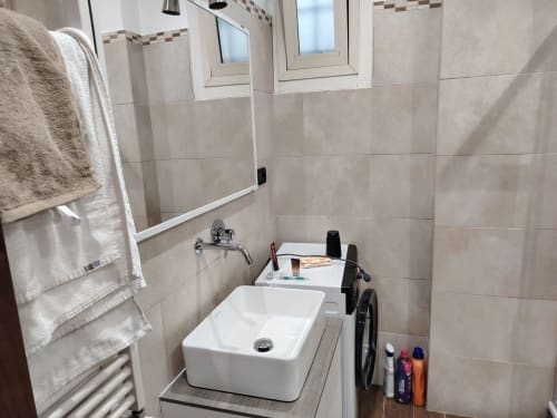 Bagno moderno nell'appartamento ViOletta con lavabo rettangolare bianco, pareti piastrellate e servizi igienici a Lido di Ostia