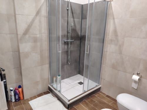 Bagno moderno con doccia in cristallo, pareti in piastrelle beige, pavimento effetto legno scuro e toilette dell'hotel ViOletta a Lido
