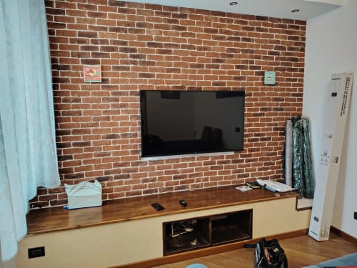 Camera d'hotel ViOletta Roma con TV a parete su mattoni a vista, consolle in legno e scaffalature incassate