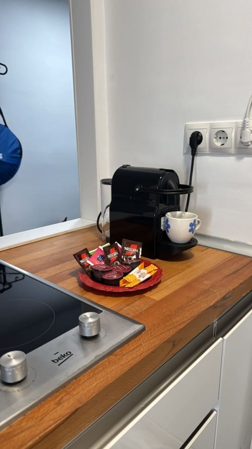 Encimera de cocina con cafetera Nespresso negra, taza blanca y cápsulas Nescafé en el apartamento Torre Sol Y Playa