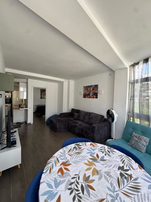Apartamento moderno en Torre Sol Y Playa, Torremolinos con cama azul, sofá oscuro, cocina y vistas al mar