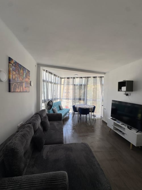 Moderna sala de estar del hotel Torre Sol Y Playa en Torremolinos con balcón, sofá gris y mesa de comedor
