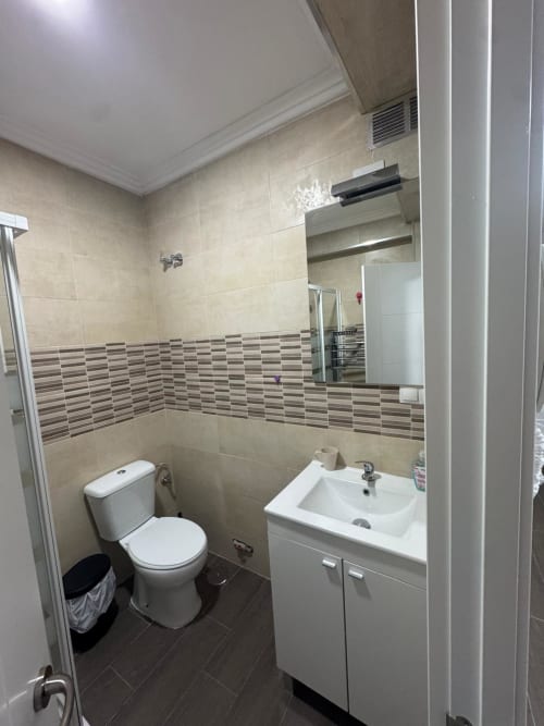 Cuarto de baño moderno del hotel Torre Sol Y Playa en Torremolinos con lavabo blanco, inodoro y azulejos decorativos a rayas