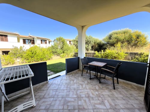 Terrazza coperta con zona pranzo che affaccia sul giardino verde della villa Villetta 1 a Valledoria, Italia