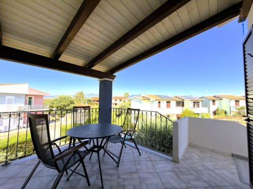 Patio privato con tavolo da pranzo e sedie con vista sulle colorate case del villaggio di A Mare Case Vacanze a Valledoria