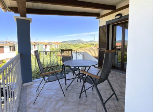 Terrazza coperta con tavolo da pranzo e sedie con vista sul giardino presso A Mare Case Vacanze, Valledoria