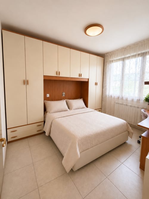 Camera moderna in Appartamento Lisa presso Residenza Sant'Antonio, Sottomarina, con letto, guardaroba crema e dettagli in legno