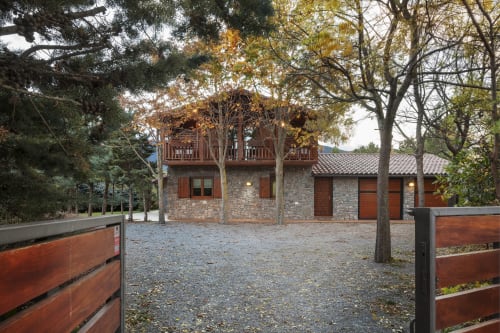 El Refugi de les Basses, edifici de pedra amb terrassa de fusta envoltat d'arbres tardorals a Campelles