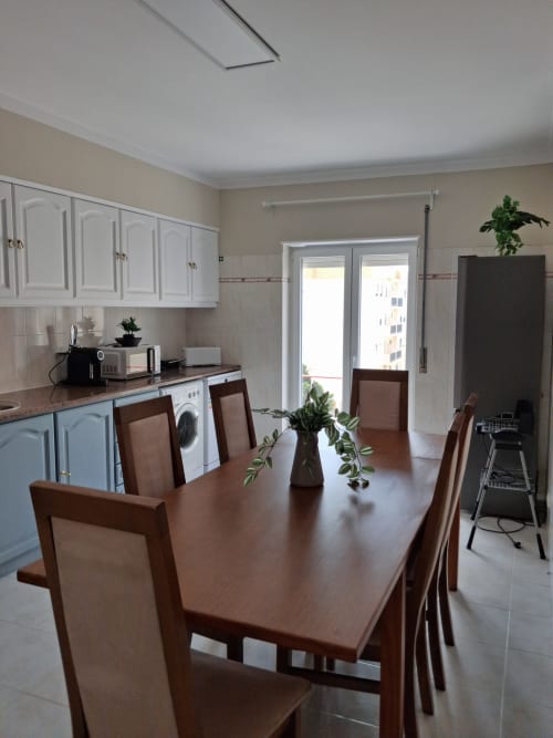 Moderne Küchen-Esszimmer im Apartment Tininha da Ilha, Lourinhã mit Holztisch, weißen Schränken und Türen mit Stadtblick