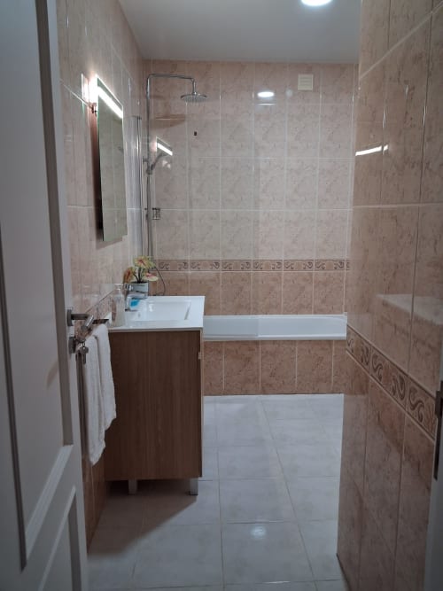 Modernes Badezimmer mit ebenerdiger Dusche, weißem Waschtisch und beigen Fliesenwänden in der Furnaka Village Herberge in Lourinhã