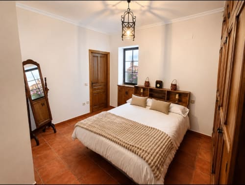 Dormitorio espacioso en la casa rural La Herrería con cama queen size, muebles de madera, suelos de barro y decoración tradicional