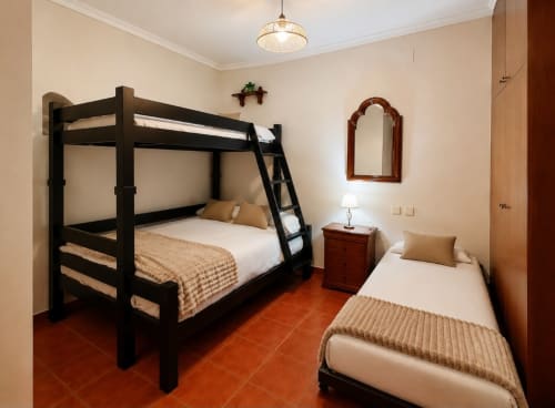 Acogedora habitación de cabaña con cama litera negra, cama individual, piso de terracota e iluminación cálida en Casa Rural La Herrería