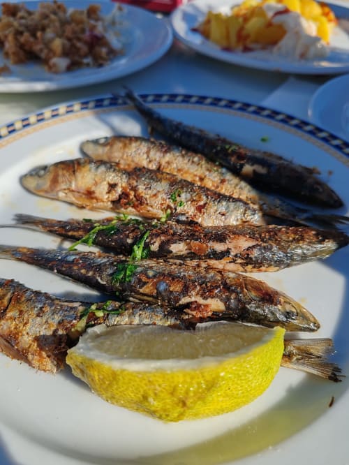 Grilled sardines with lemon garnish, served at Lisbon Poets Inn hostel in Lisboa