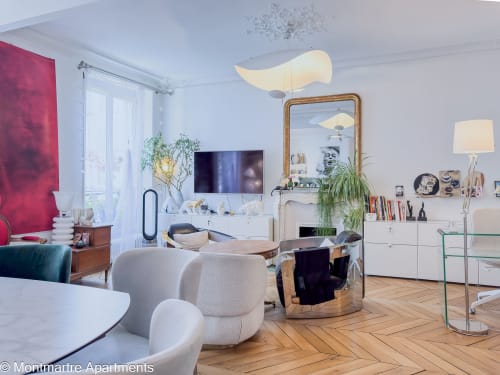 Modern Parisian apartment living room with cream furniture, wooden herringbone floors, and artistic decor at Montmartre