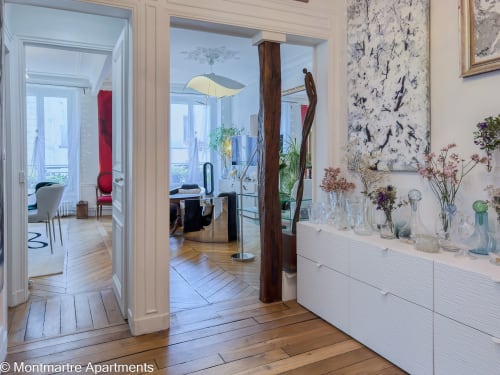 Montmartre Apartments Paris: Paradis Artistique apartment with wooden floors, white dresser, flowers, and open layout with