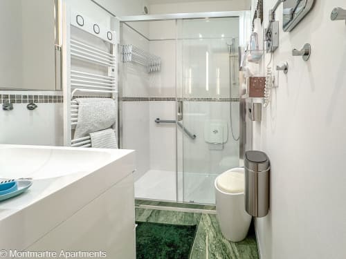 Modern bathroom in Montmartre Apartments Paris with shower, toilet, sink, heated towel rack and contemporary finishes