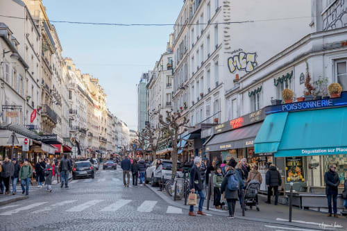 Bustling Parisian street in Montmartre with shops, cafes, and pedestrians along cobblestone avenue