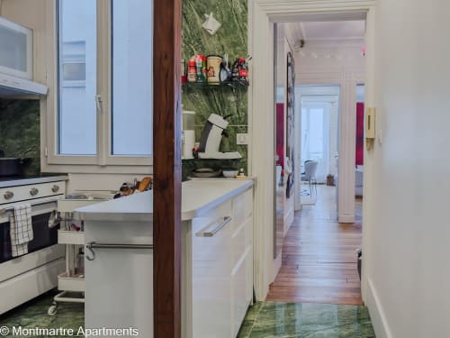 Modern kitchen in Montmartre Apartments Paris with white cabinets, stainless steel appliances, and wooden flooring