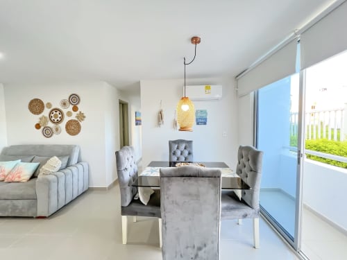 Apartamento moderno en Olamar Living con sillas de comedor grises, luminaria colgante tejida y balcón con vista al jardín en Coveñas
