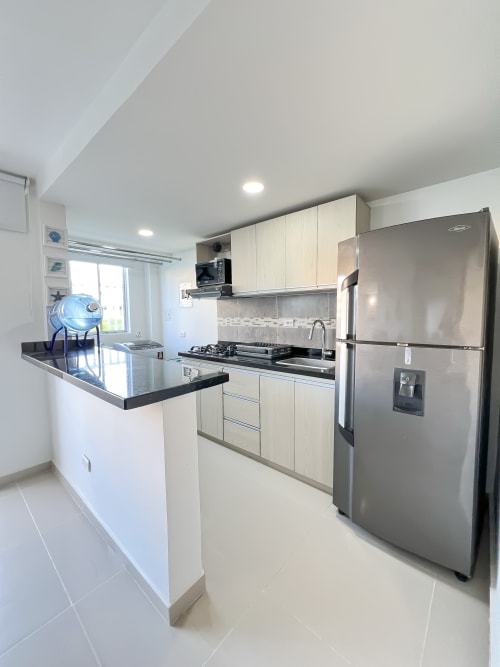 Cocina moderna en apartamento Mar Azul de Olamar Living, Coveñas con electrodomésticos de acero inoxidable y encimeras negras