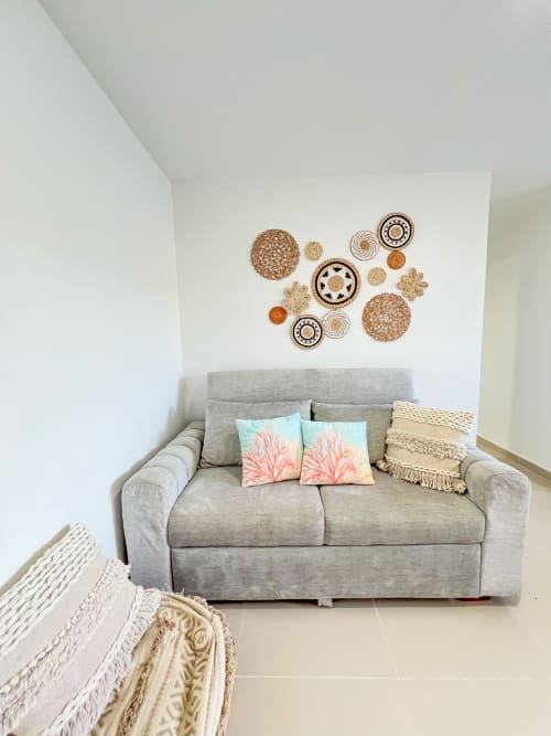 Sofá tapizado gris con cojines coral en el apartamento Mar Azul de Olamar Living, Coveñas, Colombia, con decoración bohemia en la pared