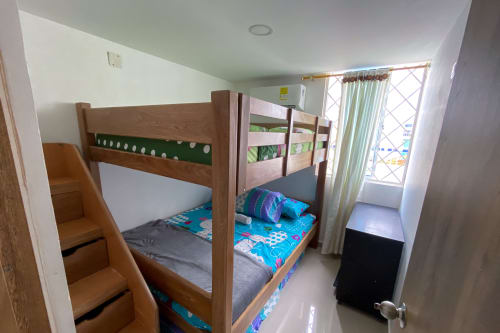 Habitación con literas de madera en apartamento Olamar Living de Coveñas, ropa de cama colorida y puerta con vista al jardín